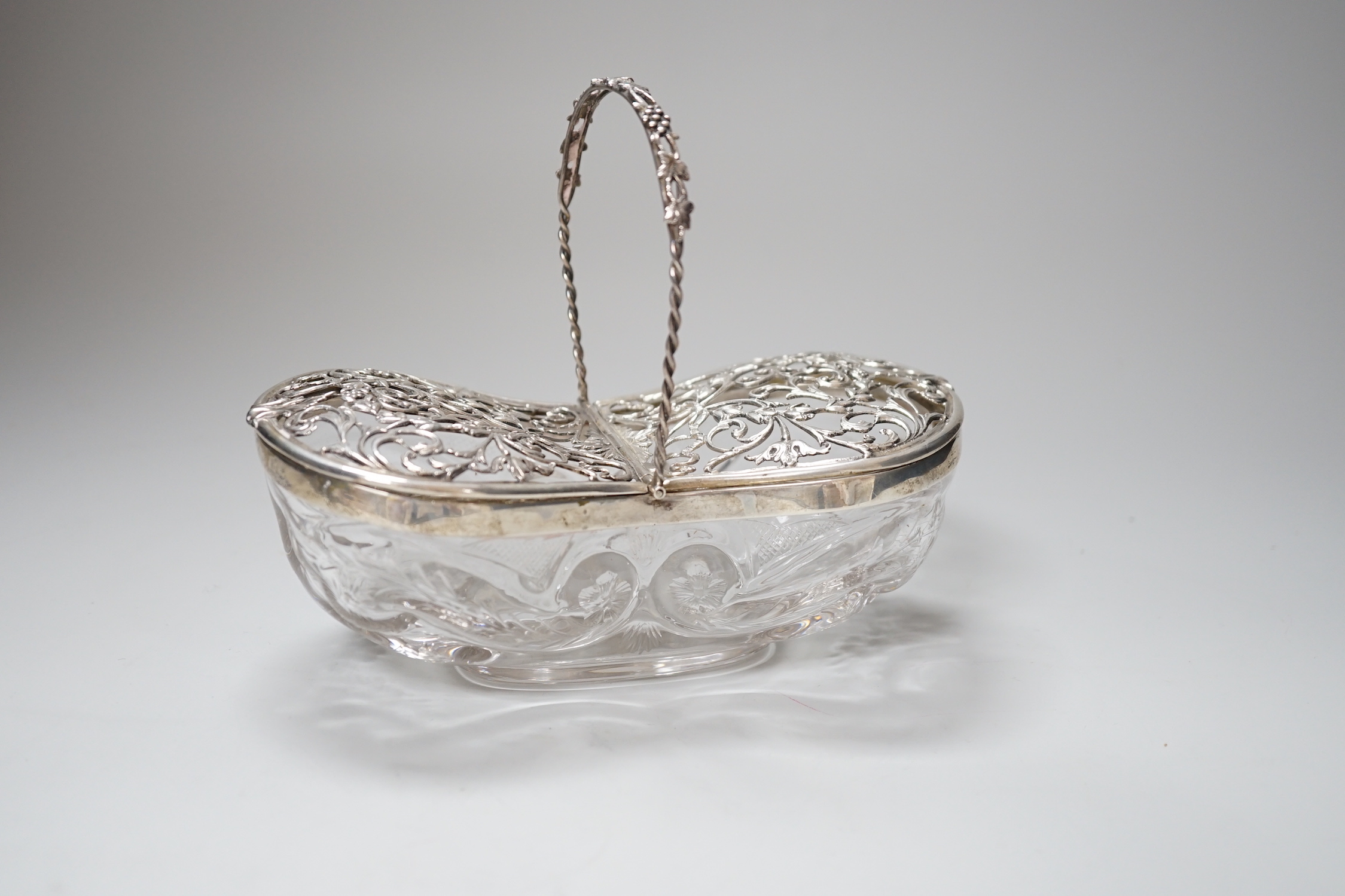 A George V silver mounted Stoubridge glass bon bon basket, with swing handle and two foliate scroll pierced hinged lids, Charles & Richard Comyns, London 1918, 17cm